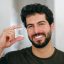 A young man holding a dental teeth aligner in a home.